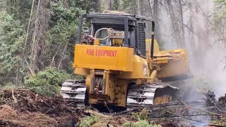 Bulldozers and firefighters cut a line near the Pogo Mine Road Fire Wednesday to protect private property and powerlines near the fire.