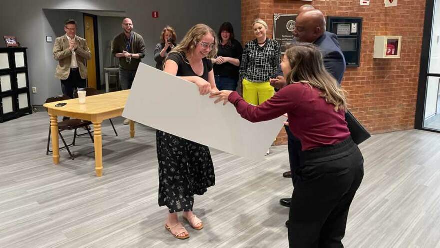 A young woman is receiving an award. She is smiling and crying while accepting her award.
