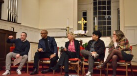 Five people sit on chairs talking with one another.