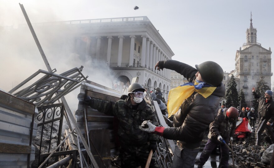 An anti-government protester throws a stone during clashes in Kiev. At least 26 people were killed Tuesday and an additional 241 were injured on Tuesday, according to The Associated Press.