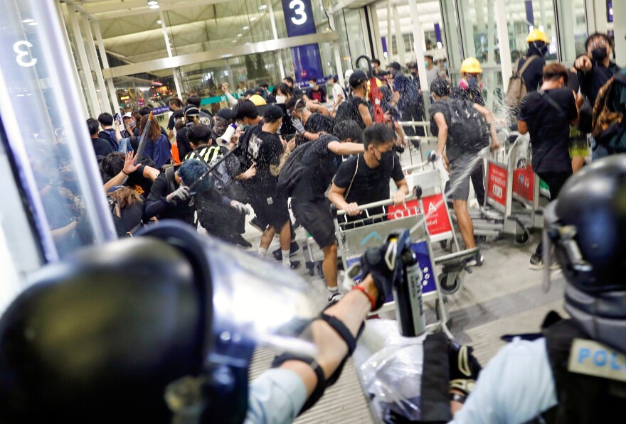 Riot police use pepper spray to disperse protesters during a mass demonstration at the Hong Kong International Airport.