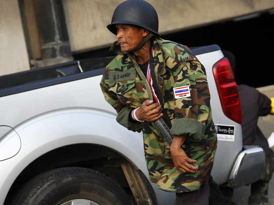 An anti-government protester hides his rifle under a jacket during a gunfight in the capital on Saturday.