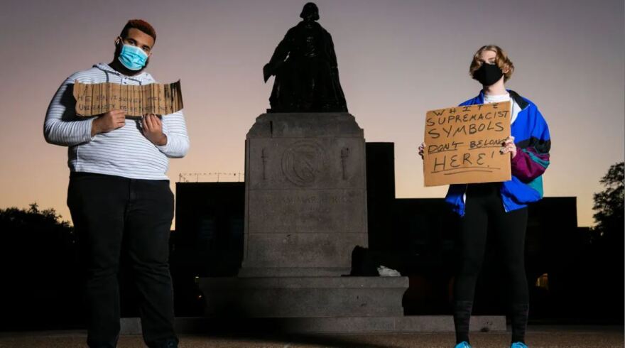 Shifa Rahman, left, and Blaise, who declined to share a last name, hold signs at the base of the William Marsh Rice statue on the campus of Rice University in Houston. Rahman has spent an hour on campus nearly every day since August calling for the removal of the statue.