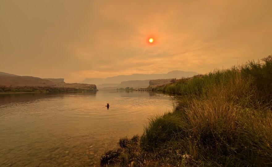 Visitors to Lees Ferry still recreate despite a sun made red by wildfire smoke.
