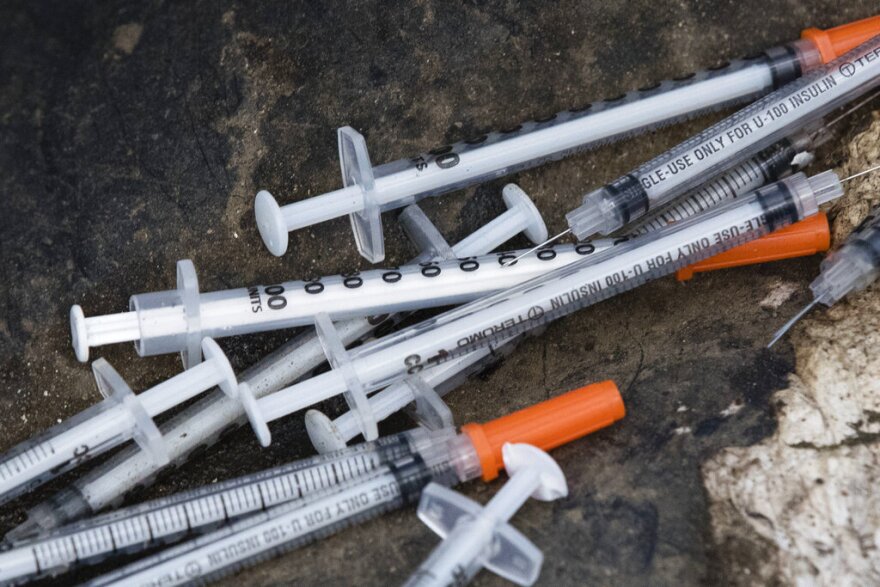 This July 31, 2017, file photo shows discarded syringes in an open-air heroin market that has thrived for decades, slated for cleanup along train tracks a few miles outside Philadelphia.