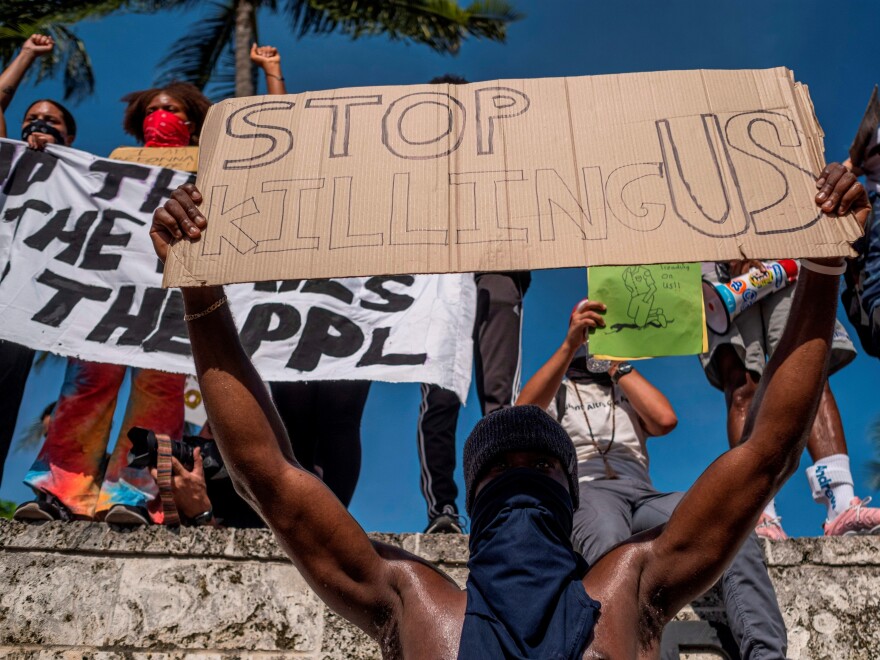 Protesters in Miami hold signs during a rally Sunday in response to the recent death of George Floyd.