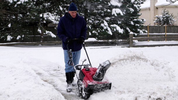 A man clears the snow in front of a house during a cold weather day, Sunday, Dec. 7, 2025, in Glenview, Ill. (AP Photo/Nam Y. Huh)