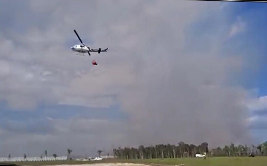 A firefighting helicopter that picks up a huge bucket of water and drops it on a wildfire works on the Newman Fire last week, east of Naples in Collier County