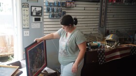 Kaylyn Boyd carries a framed photograph from her father's flooded sports card shop in Cambridge City, Ind., Thursday, Aug. 13, 2026.