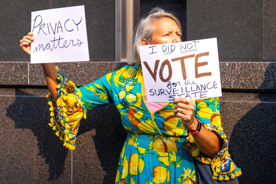A protester holds up anti-Flock placades outside Richmond City Hall during a demonstration against Flock cameras before a City Council meeting on July 27, 2026.
