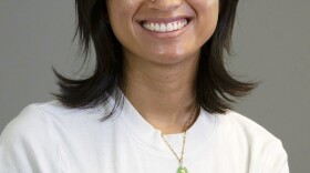 A person sits against a gray background looking at the camera.