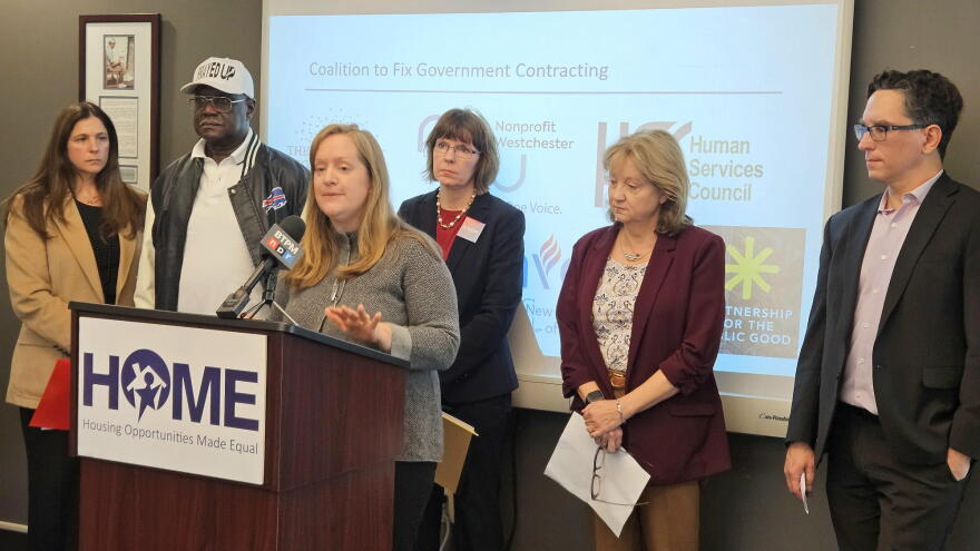 Partnership for the Public Good Executive Director Andrea Ó Súilleabháin, standing at lectern, lays out her concerns with how long it often takes the state to make payments for contracts with nonprofit organizations.