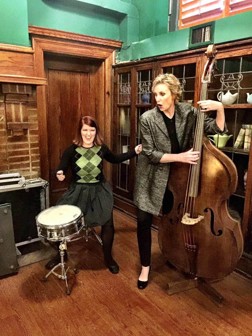 A woman plays a drum kit while another woman plays the upright bass.
