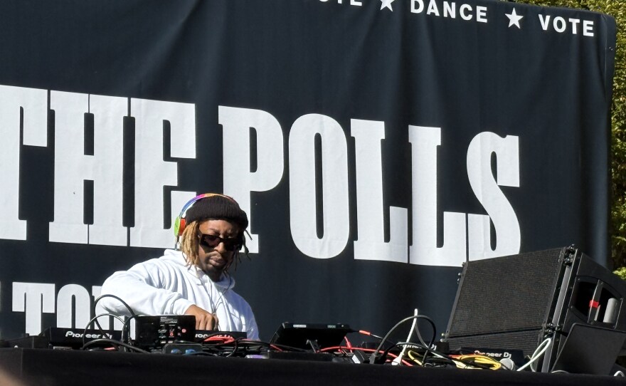 A close-up of a man wearing headphones and tending to DJ equipment.
