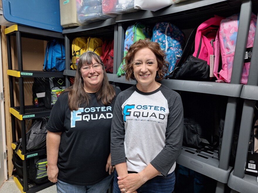 Kate Pauley (left), Foster SQUAD's board president and Traci Schermerhorn, co-found and executive director, stand in front of Foster Care Kits ready to be handed out to Iowa foster kids and teenagers.