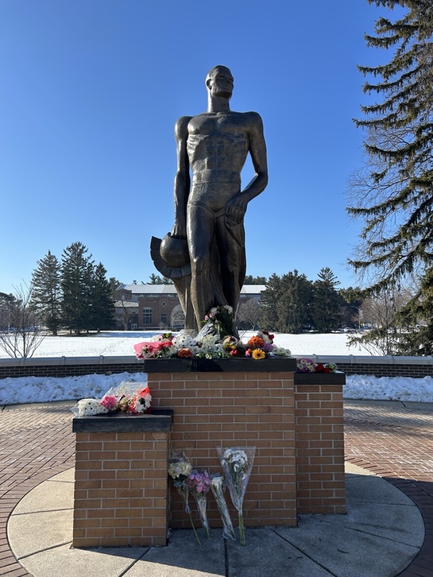 Flowers cover the base of the Spartan statue outside Spartan Stadium in honor of the 2023 campus shooting victims.