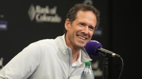 Paul DePodesta speaks into a purple microphone.