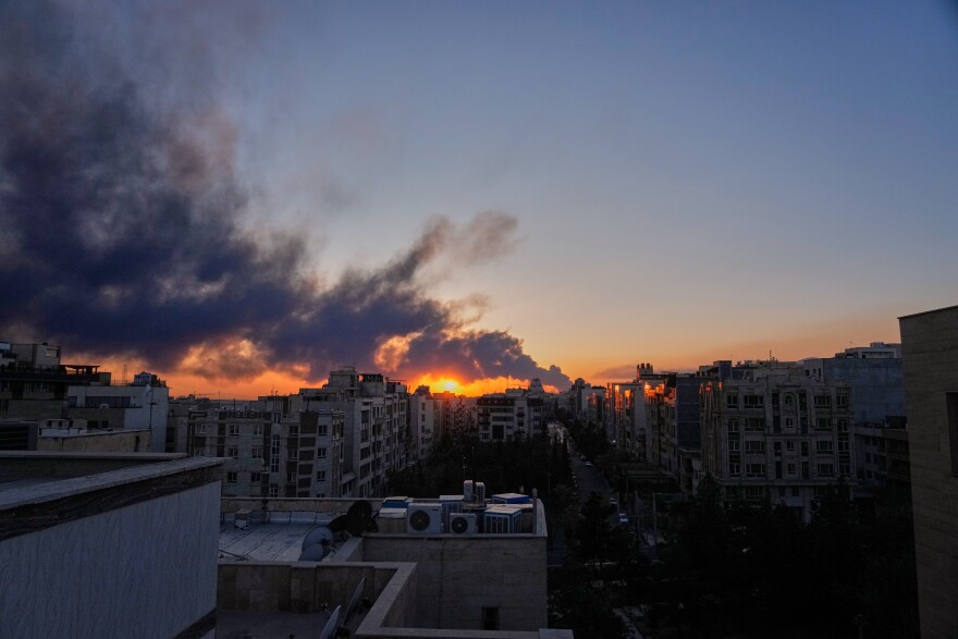 The sun sets behind a plume of smoke rising after a U.S.–Israeli military strike in Tehran, Iran, Tuesday, March 3, 2026.