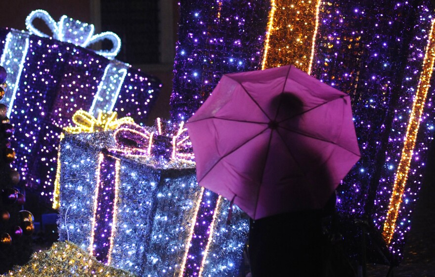 People walk past Seasonal decorations on a rainy evening in Warsaw, Poland, Tuesday, Dec. 23, 2014, one day ahead of Christmas Eve. Weather forecasts predict a rainy Christmas in Poland. (AP Photo/Alik Keplicz)
