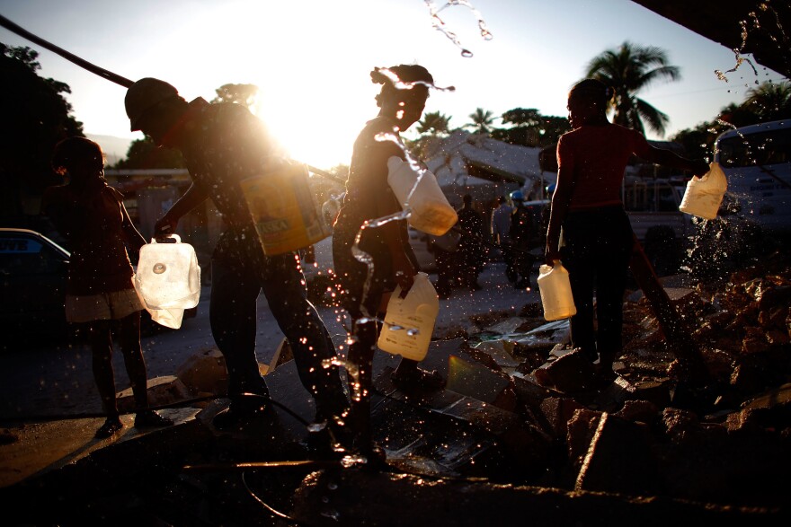 With fresh water in short supply, men and women gather around broken pipes to collect drinking water in Port-au-Prince in the days following the quake.