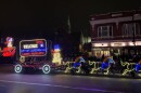 A lighted Christmas float with Snoopy, a Carbondale logo, Snowman and horses leading the float pictured at night during a parade.
