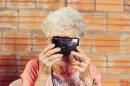 Old woman holds up a film camera to her face