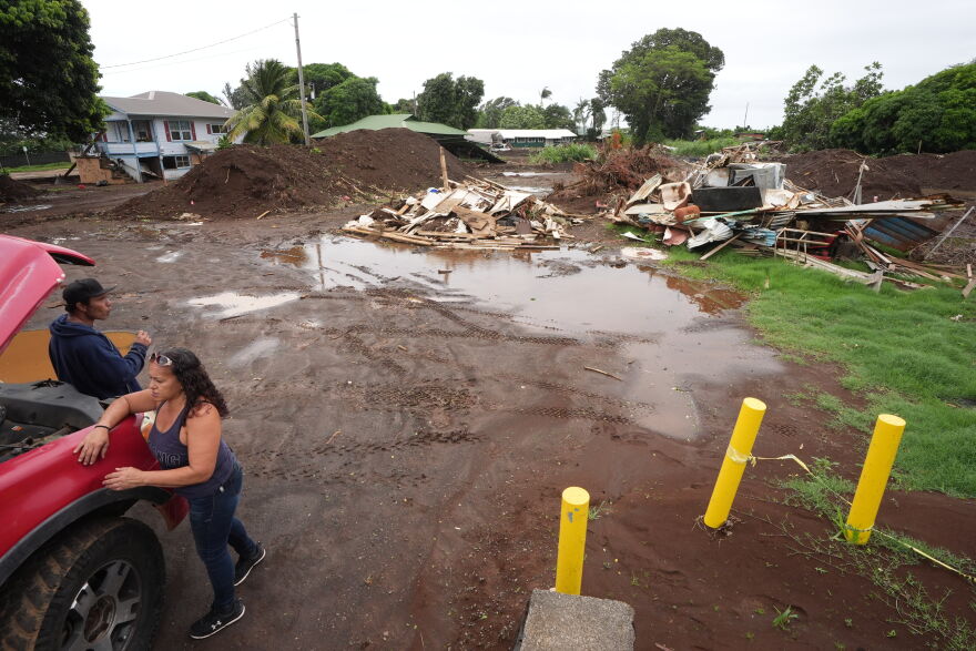 A couple waits for battery cables to start their truck near where a home was destroyed during last month's Hurricane Lala, as floodwaters from Hurricane Nolo recedes Sunday, Sept. 27, 2026, in Naalehu, Hawaii. (AP Photo/Gregory Bull)