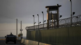 A U.S. trooper stands in the turret of a vehicle with a machine gun, left, as a guard looks out from a tower, in this 2010 photo of Guantanamo Bay U.S. Naval Base in Cuba. (Brennan Linsley/AP)