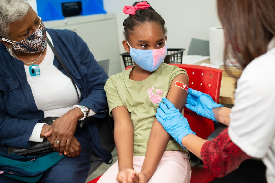 A CVS pharmacist applies a band-aid after giving a vaccine to a child.