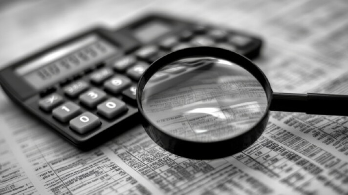 Stock photo depicting a magnifying glass, a calculator and financial documents.