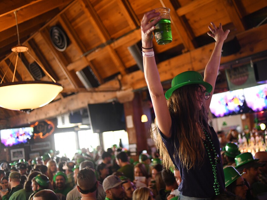 A woman dances while sitting on her friend's shoulders during St. Patrick's Day festivities in Denver last year.