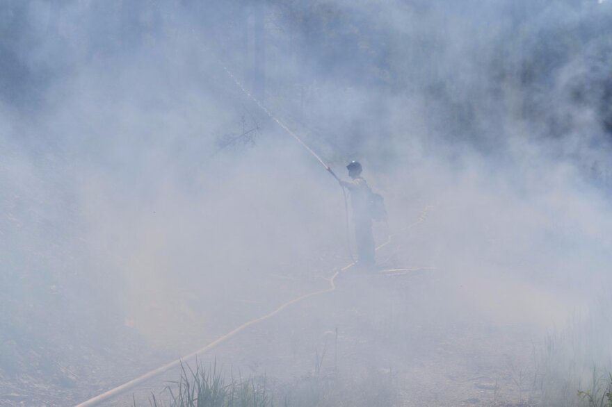 A firefighter douses puts out live embers upslope of a prescribed burn near Lakeside to block the fire from spreading