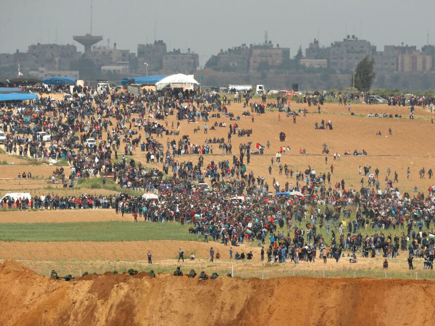 From the southern Israeli kibbutz of Nahal Oz, Palestinians can be seen participating in the "March of Return" protests, under the alert eyes of Israeli soldiers, in the foreground.