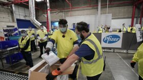 Pfizer workers pack boxes with the COVID-19 vaccine.