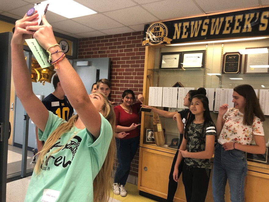 Junior Phoenix Bialek takes a selfie with the freshmen she's leading on a scavenger hunt around Shawnee Mission West High School.