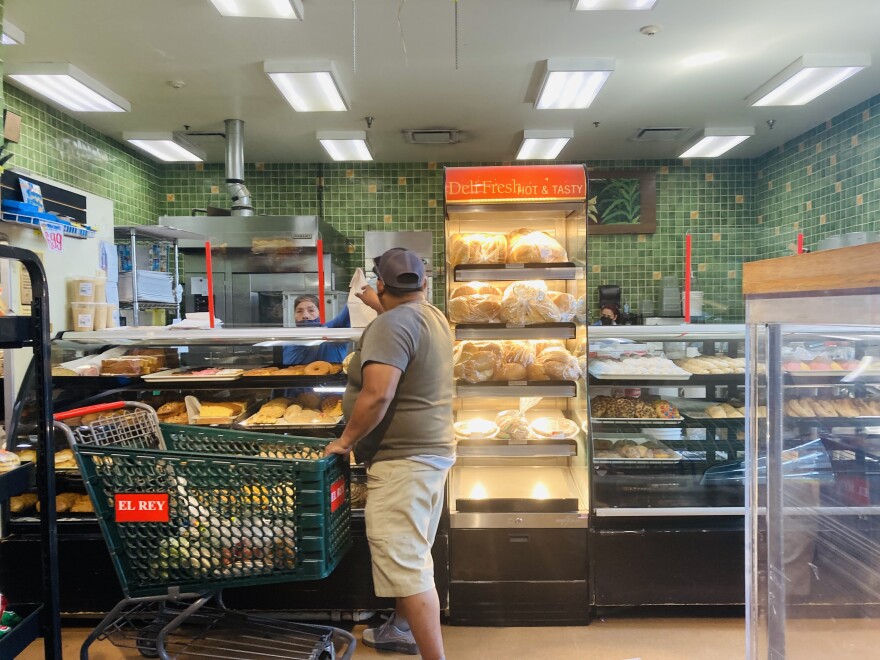  a man in a baseball cap reaches over a counter to pick up a bag of treats from El Rey's bakery