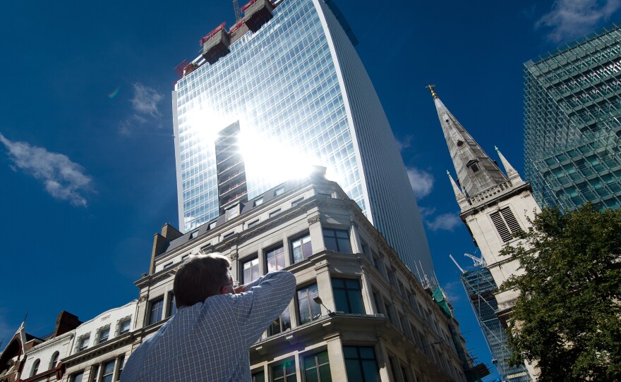 A man reacts to a shaft of intense sunlight reflected from the glass windows of the new "Walkie Talkie," or "Walkie Scorchie," tower in central London on Aug. 30, 2013.