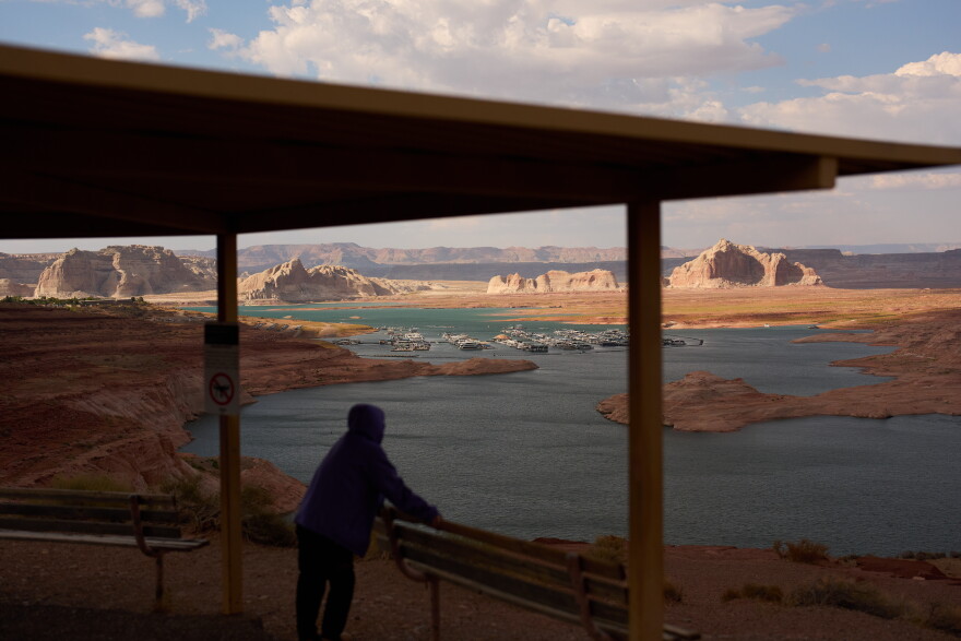 FILE - A person stands at an overlook near the Wahweap Marina on Lake Powell at the Glen Canyon National Recreation Area, July 15, 2026, near Page, Ariz. (AP Photo/John Locher, File)
