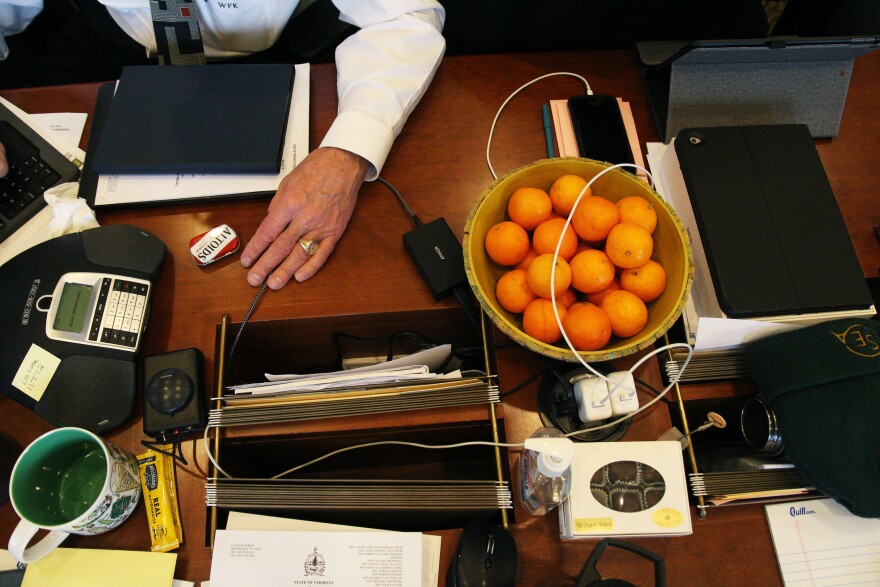 An aerial view of a table with a bowl of clementines and person seated nearby