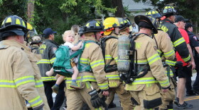 A Grapevine firefighter marches through town with a toddler strapped to his back. Multiple attendees highlighted the importance of passing on the lessons of 9/11 to the next generation. Sept. 11, 2026.