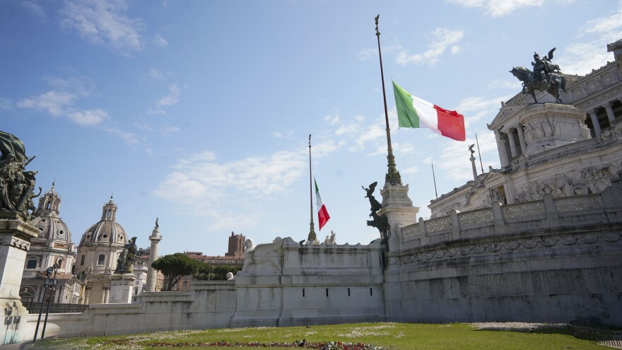 During a minute of silence commemorating COVID-19 victims, flags fly at half-staff Tuesday at Rome's monument to the unknown soldier.