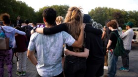 People stand arm-in-arm in a crowd.