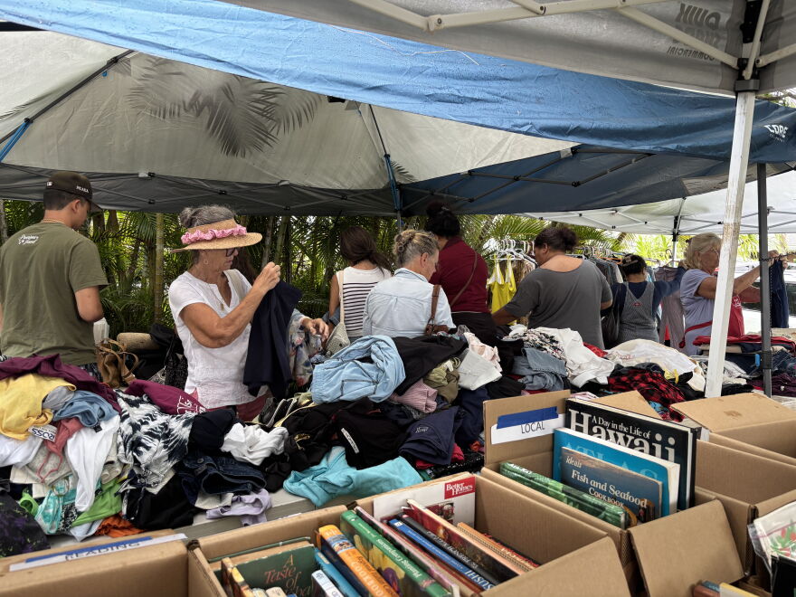 Community members, many of whom come to every annual garage sale, sort through the clothing section of the sale in front of Wells' home.