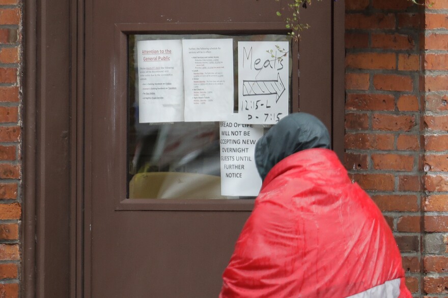 In this file photo from March, a man carrying a sleeping bag looks at a sign on the door of the Bread of Life Mission in Seattle's downtown Pioneer Square neighborhood. COVID-19 cases have risen in King County’s homeless population throughout the summer.