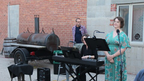 Vocalist Lauren Storm provides context for the piece she is about to sing at at Hutchinson’s Sandhills Brewing.