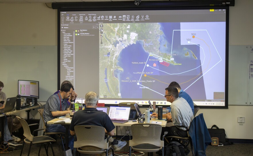 Silent Swarm officials work on coordinating their teams during the simulation. The map projected in the Silent Swarm headquarters at the Great Lakes Maritime Heritage Center shows where vessels are in Lake Huron.