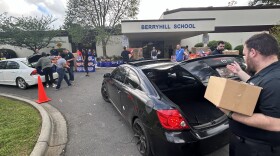 Volunteers with Second Harvest Food Bank of Metrolina load cars with groceries at Berryhill Elementary School.
