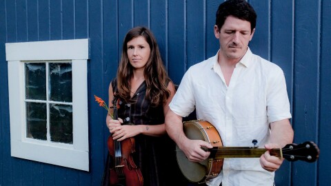 Two people holding instruments, a banjo and violin. 