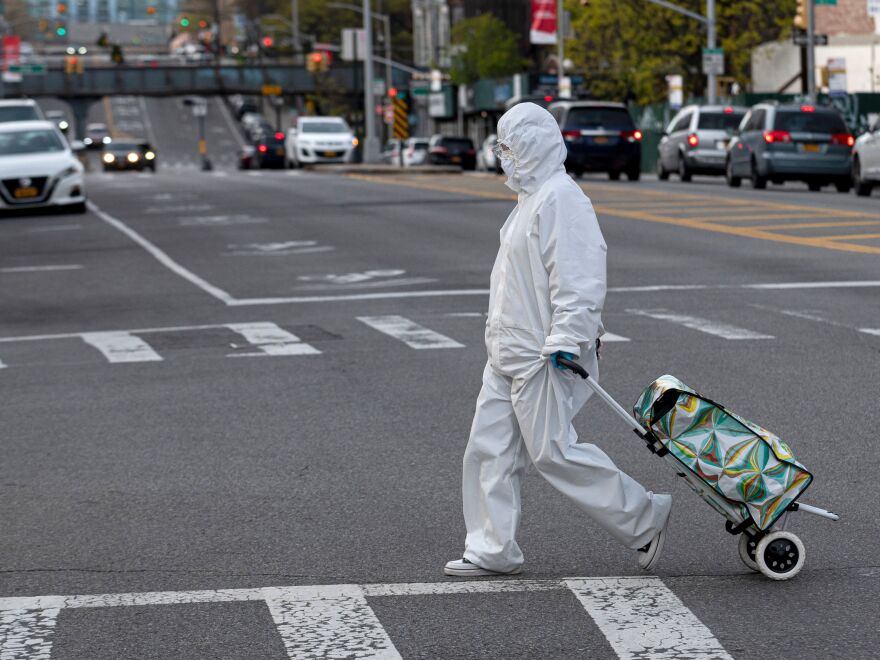 A woman wearing a hazmat suit pulls her grocery cart in the streets in New York City amid the coronavirus pandemic.