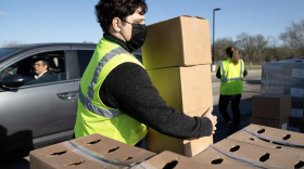 Baron Reedy loads a box of food provided by the Central Texas Food Bank into a vehicle during a drive-thru distribution event in Austin. As food prices rise for consumers, food banks are also dealing with their own financial squeeze caused by inflation and a decline in donations as they wait for the disbursement of already approved federal aid.